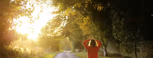 Pathway to Becoming a Greater Self A person embraces the sunrise on a tranquil path, symbolizing the awakening journey towards self-improvement and leadership growth.