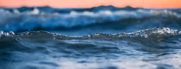 Rising Tides of Leadership Growth Waves crest in the twilight, symbolizing an emerging leader's journey through challenges towards the light of self-improvement.