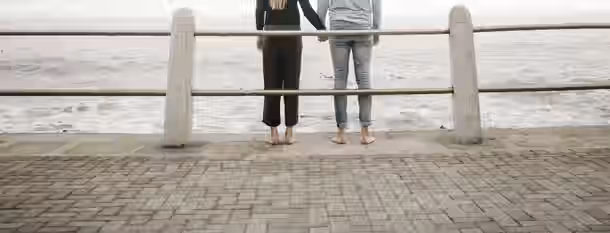 Together Towards the Horizon Two individuals holding hands, facing an endless ocean, symbolize mutual support and the journey towards self-improvement and leadership.