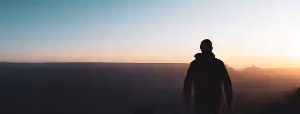 Ascending Horizons: A Leader's Path to Growth A silhouette stands on a vast horizon, facing a sunrise that symbolizes new beginnings and the journey of an emerging leader.