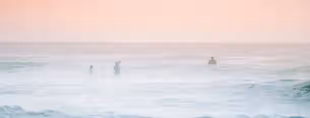 Navigating the Misty Waters of Leadership Individuals braving the vast, misty ocean at dawn, symbolizing the journey of emerging leaders navigating towards self-improvement.