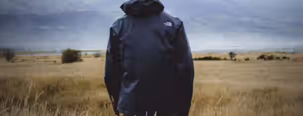 Facing the Horizon: A Leader's Quest for Growth Standing alone in a vast field, looking toward the horizon, symbolizing an emerging leader's journey to self-improvement.