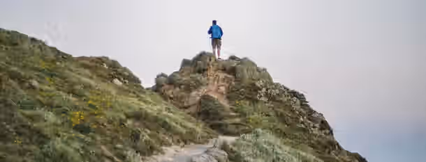 Ascending New Heights: Path to Self-Leadership A person stands atop a rugged hill, symbolizing the peak of their journey towards self-improvement and emerging leadership.