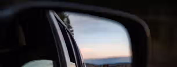 Reflections of Growth in Rearview Mirror A rearview mirror captures a glimpse of the past, while the horizon ahead symbolizes future growth and self-improvement.